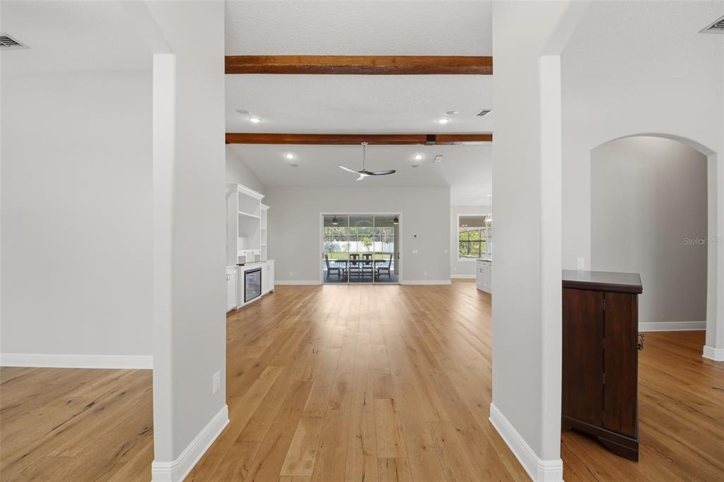 A bright, open-concept living area features light wood flooring, exposed ceiling beams, and sliding doors — 5741 BAY SIDE DRIVE, ORLANDO, FL