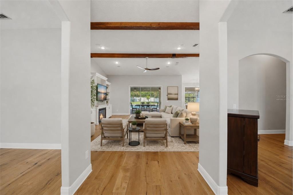 A view through an arched entryway into a living room with wood ceiling beams — 5741 BAY SIDE DRIVE, ORLANDO, FL