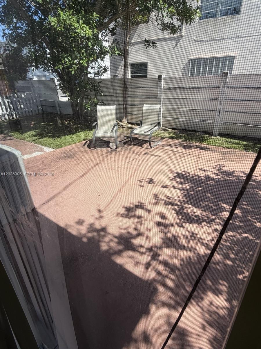 A patio with two chairs sits in a fenced backyard viewed through a screen — 812 NE 2nd St # 2, Hallandale Beach FL 33009, HALLANDALE BEACH, FL