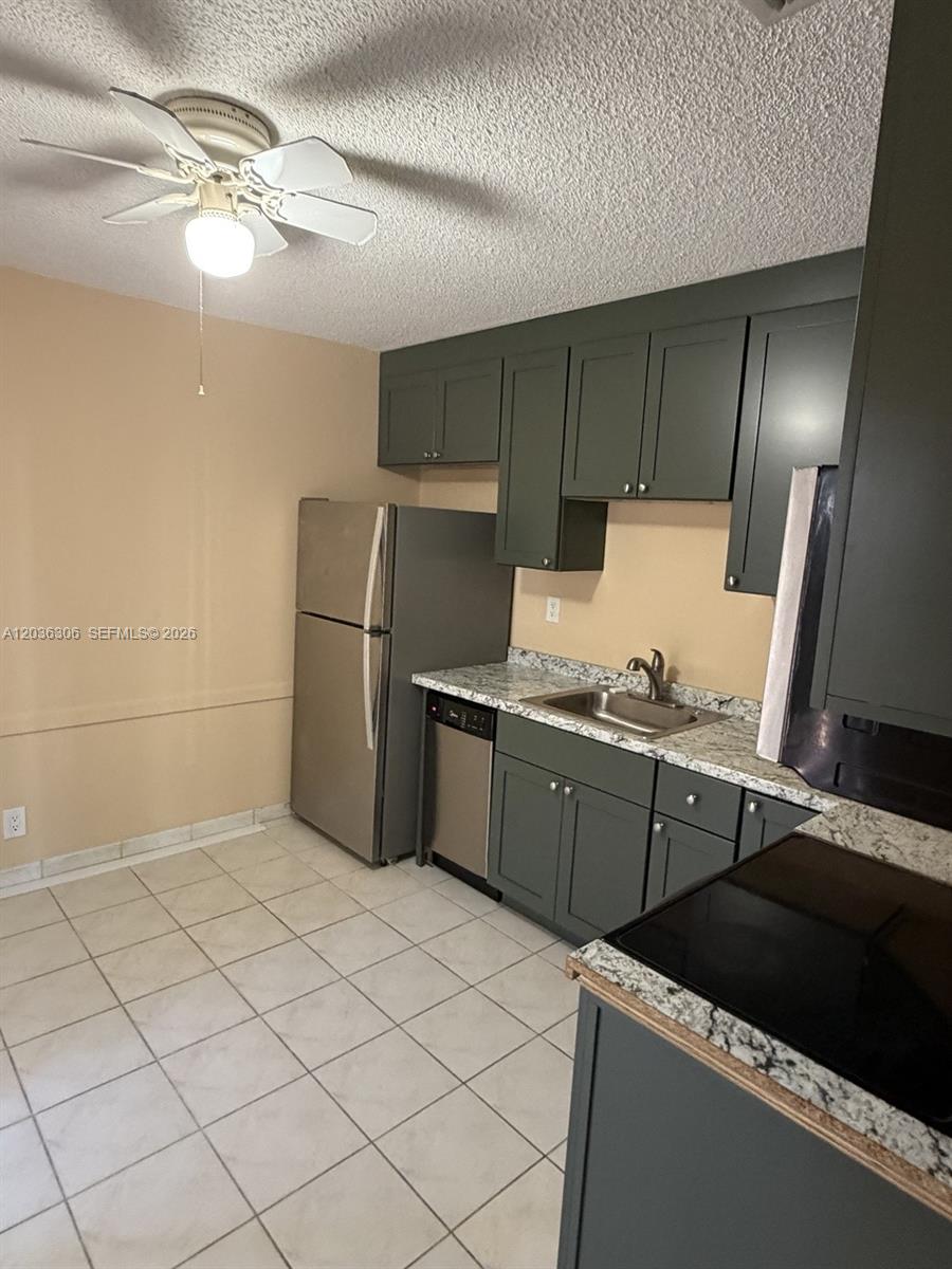 This kitchen features dark green cabinets, stainless steel appliances, and light-colored granite countertops — 812 NE 2nd St # 2, Hallandale Beach FL 33009, HALLANDALE BEACH, FL