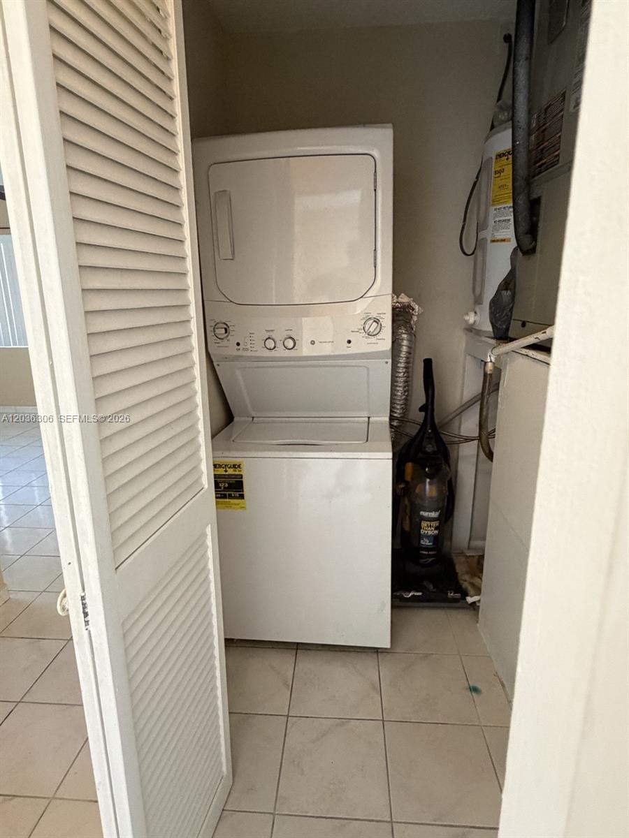 A laundry closet contains a stacked washer and dryer unit next to a water heater — 812 NE 2nd St # 2, Hallandale Beach FL 33009, HALLANDALE BEACH, FL