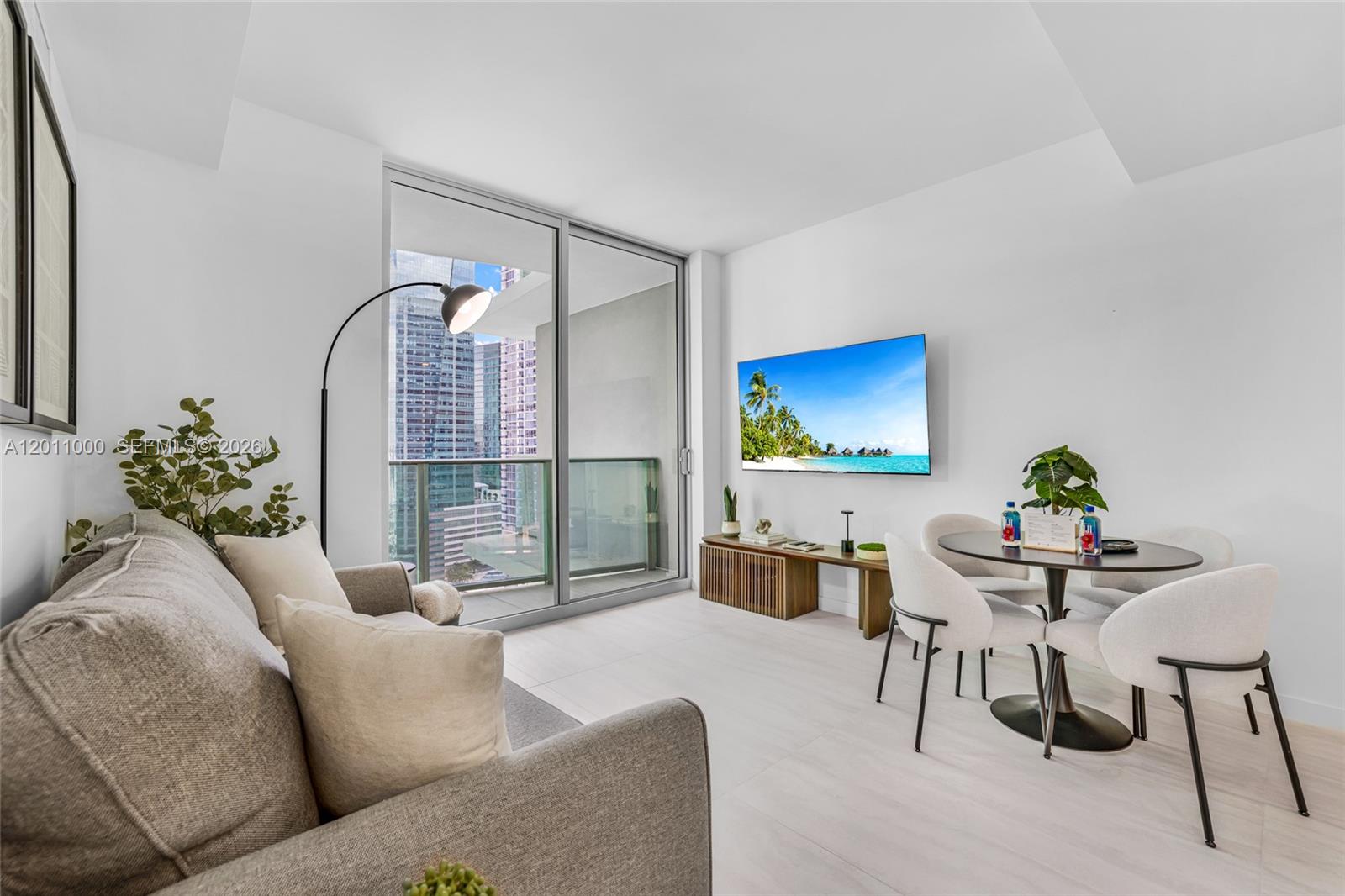 A living and dining area features a sofa, television, and balcony with city views — 77 SE 5TH ST # 3305, Miami FL 33131, MIAMI, FL