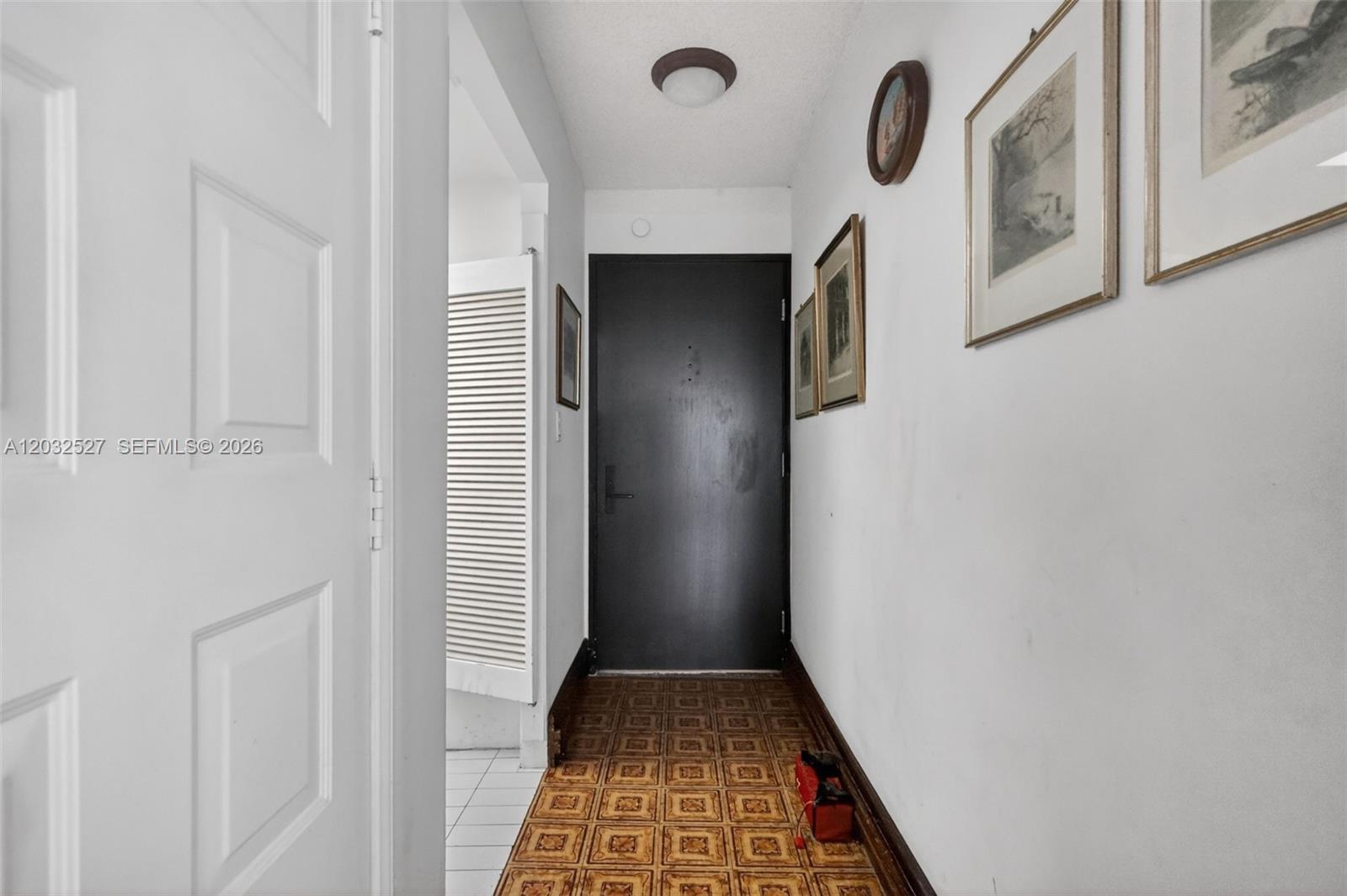 A narrow hallway features a dark front door, patterned tile flooring, and framed wall art — 2901 S Bayshore Dr # 4A, Miami FL 33133, MIAMI, FL