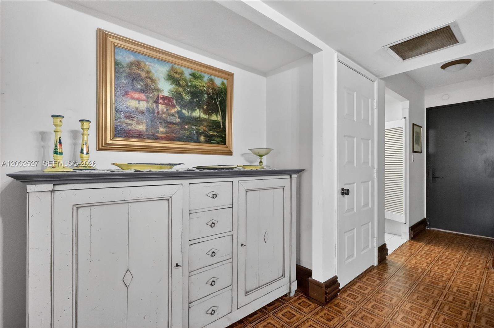 A white wooden sideboard sits against a wall beneath a landscape painting in a hallway — 2901 S Bayshore Dr # 4A, Miami FL 33133, MIAMI, FL