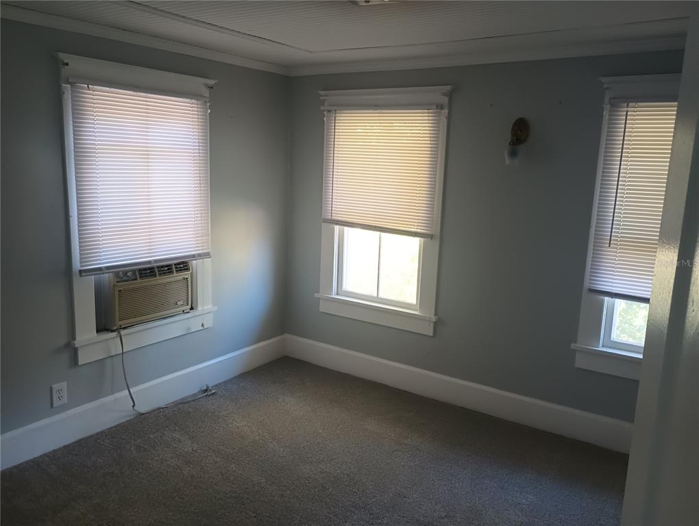 A bedroom with gray walls, carpeted flooring, three windows with blinds, and a window air conditioner — 774 32ND AVENUE N, ST PETERSBURG, FL