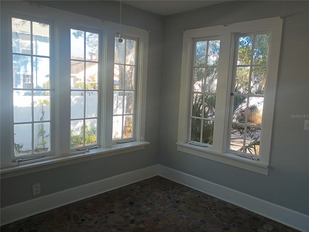 A sunroom with gray walls, white trim, multiple windows, and a patterned stone floor — 774 32ND AVENUE N, ST PETERSBURG, FL