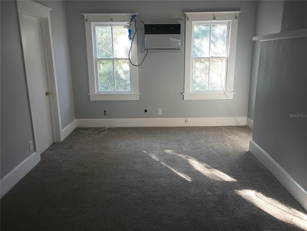 An empty bedroom features gray walls, carpeted flooring, two windows, and a wall-mounted air conditioner — 774 32ND AVENUE N, ST PETERSBURG, FL