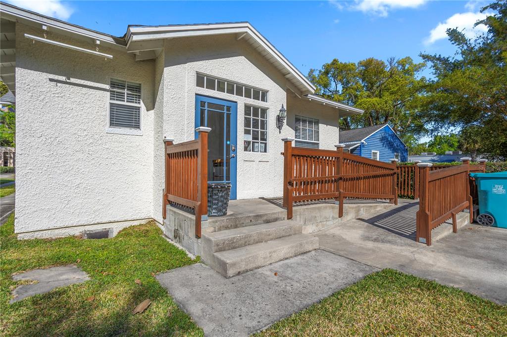 A white stucco house exterior features a blue front door, wooden railings, and a ramp — 827 IRMA AVENUE, ORLANDO, FL