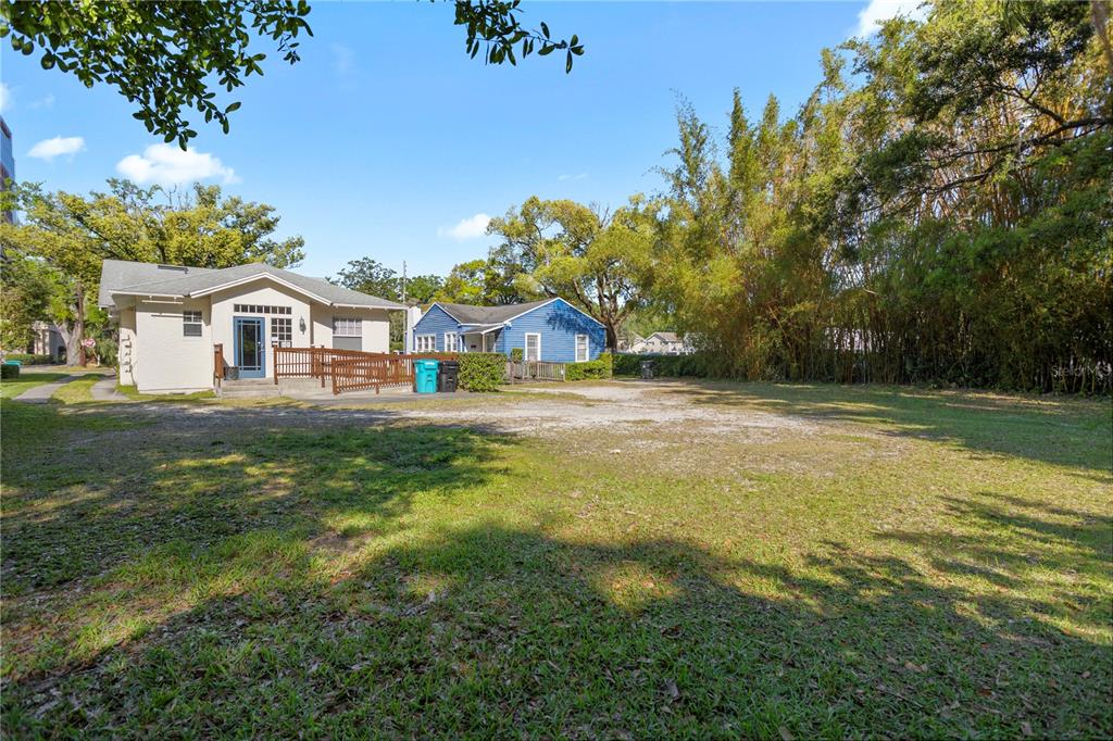 A beige house and a blue house sit behind a large, unpaved gravel lot — 827 IRMA AVENUE, ORLANDO, FL