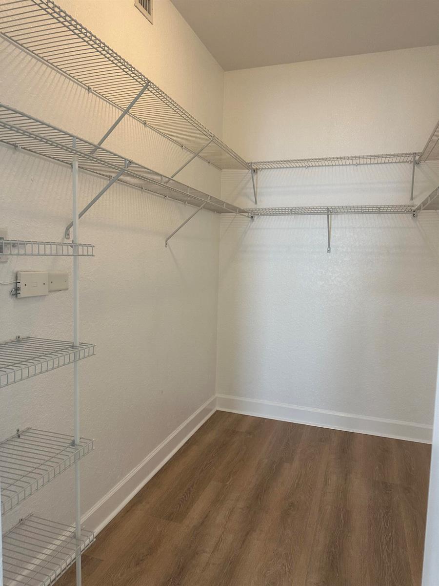 A walk-in closet with white wire shelving and light wood-look flooring — 1830 Radius Drive # 1220, Hollywood FL 33020, HOLLYWOOD, FL