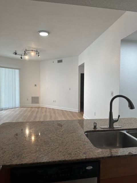 A kitchen sink with a granite countertop overlooks an open living area with wood flooring — 1830 Radius Drive # 1220, Hollywood FL 33020, HOLLYWOOD, FL