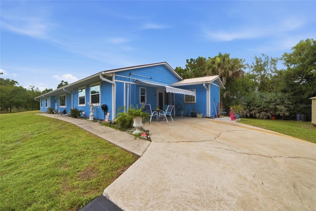 A bright blue single-story house features a concrete driveway, a patio, and a metal roof — 2300 HALL ROAD, MALABAR, FL