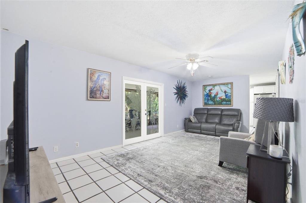 A living room features light blue walls, white tile flooring, a gray sofa, and glass doors — 2300 HALL ROAD, MALABAR, FL
