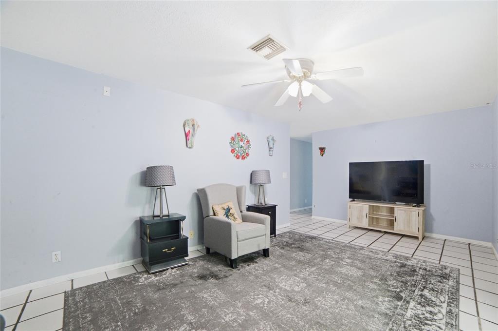 A living room features light blue walls, a gray area rug, and white tiled flooring — 2300 HALL ROAD, MALABAR, FL