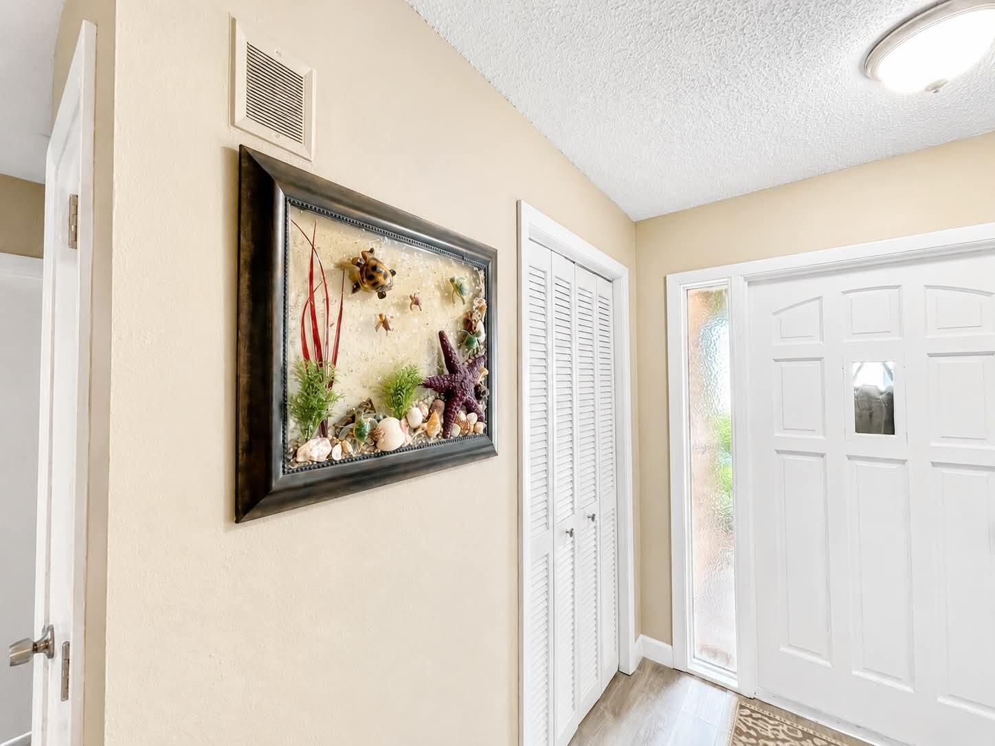 A hallway features a framed sea-themed wall art piece, white louvered closet doors, and an entryway — 15804 Missouri Street, FL 33922, FL
