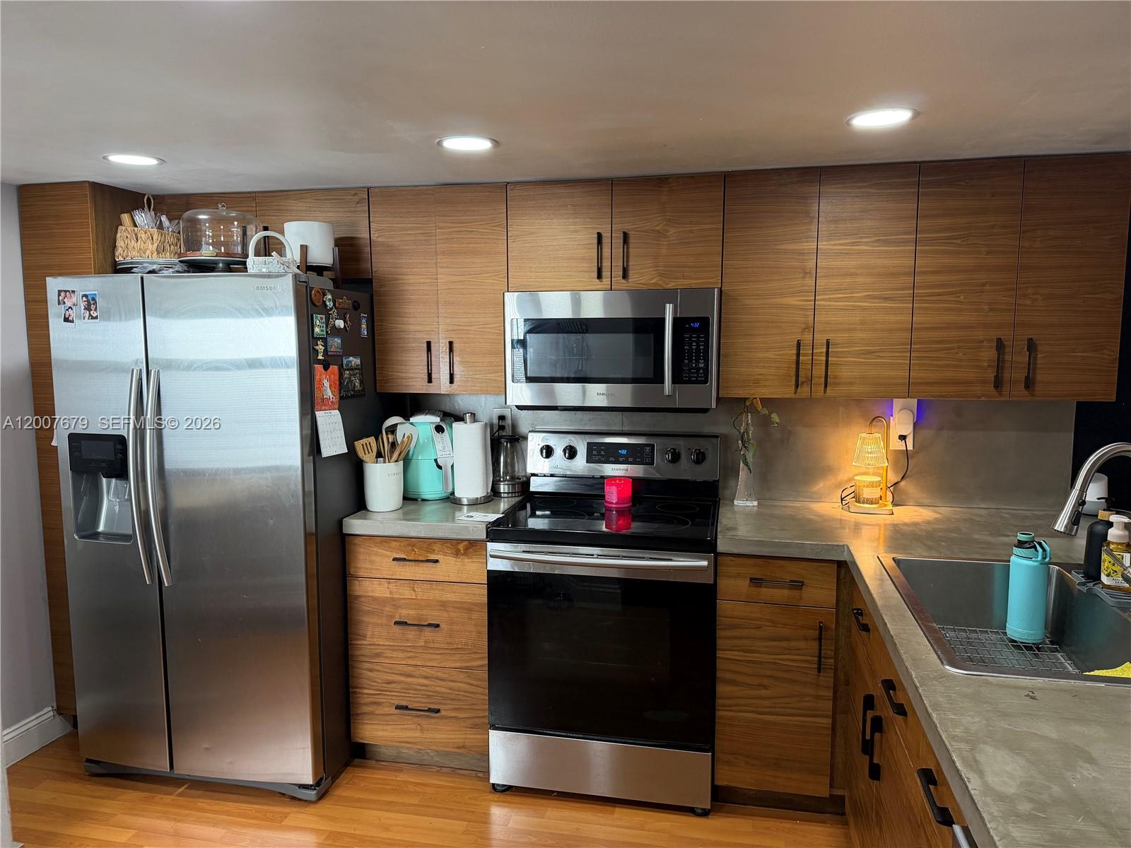 A kitchen features wood cabinets, stainless steel appliances, and concrete countertops — PEMBROKE PINES, FL