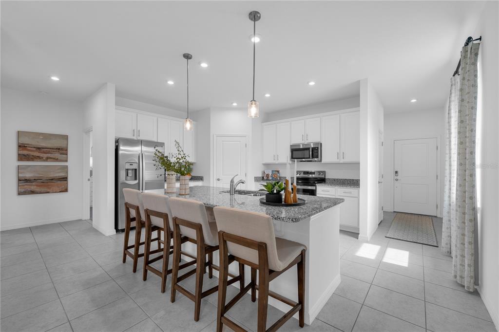 A modern kitchen features white cabinets, granite countertops, a center island with barstools, and tile flooring — 637 CASTLEFORD AVENUE NE, PALM BAY, FL