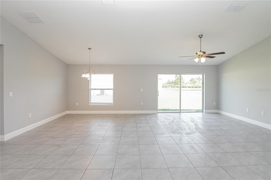 An open-concept living and dining area features light gray tile flooring and a ceiling fan — 286 BECKENHAM DRIVE, KISSIMMEE, FL