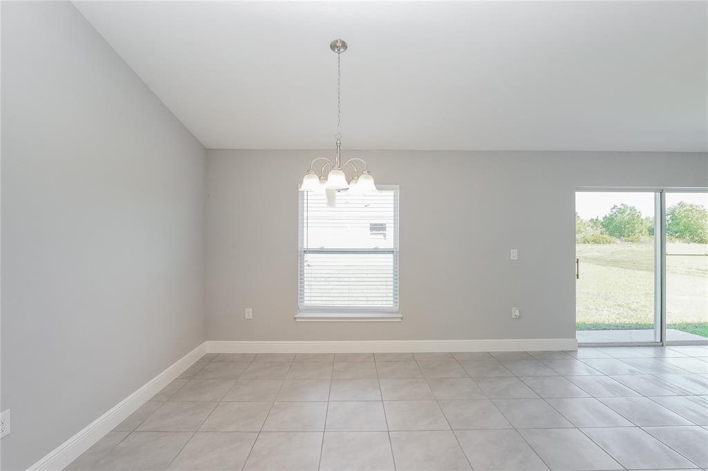 A dining area features light gray walls, large floor tiles, a chandelier, and sliding doors — 286 BECKENHAM DRIVE, KISSIMMEE, FL