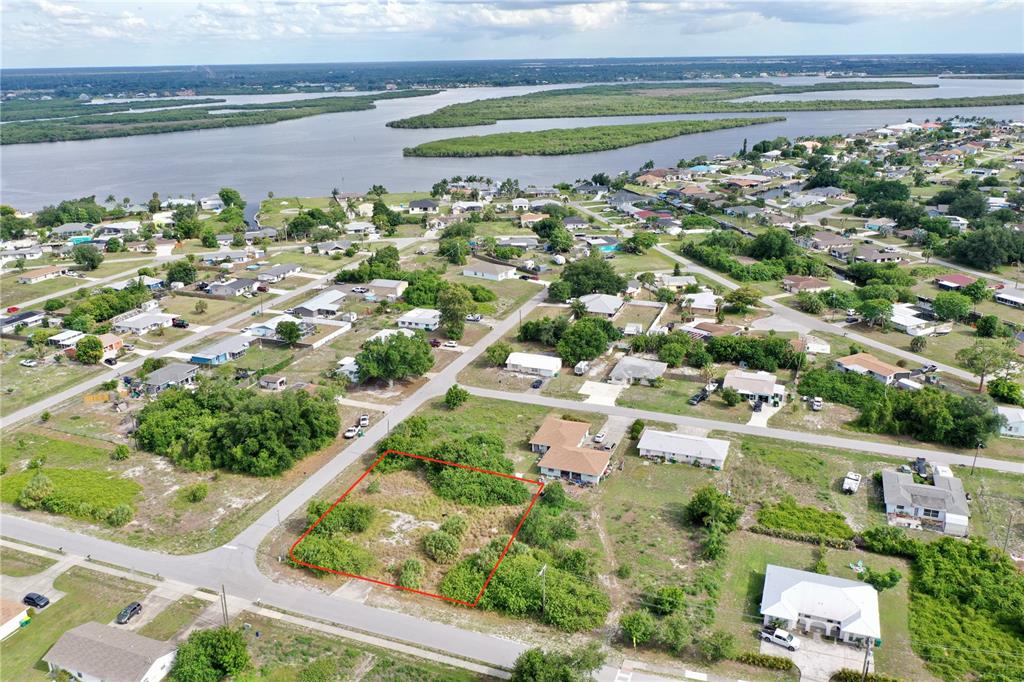 An aerial view shows a vacant, rectangular lot outlined in red within a residential neighborhood — 27147 SUNNYBROOK ROAD, PUNTA GORDA, FL