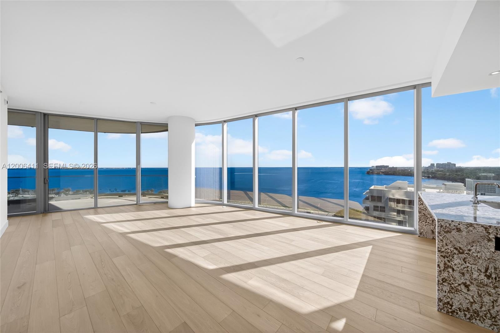 An open-plan room features light wood flooring, floor-to-ceiling windows, and a marble kitchen island — 175 SE 25th Road # 1202, Miami FL 33129, MIAMI, FL