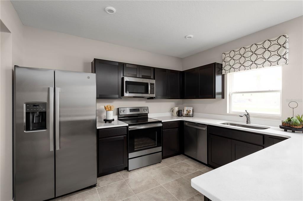 A kitchen features dark wood cabinets, stainless steel appliances, and white countertops — 11464 SE 77TH AVENUE, BELLEVIEW, FL