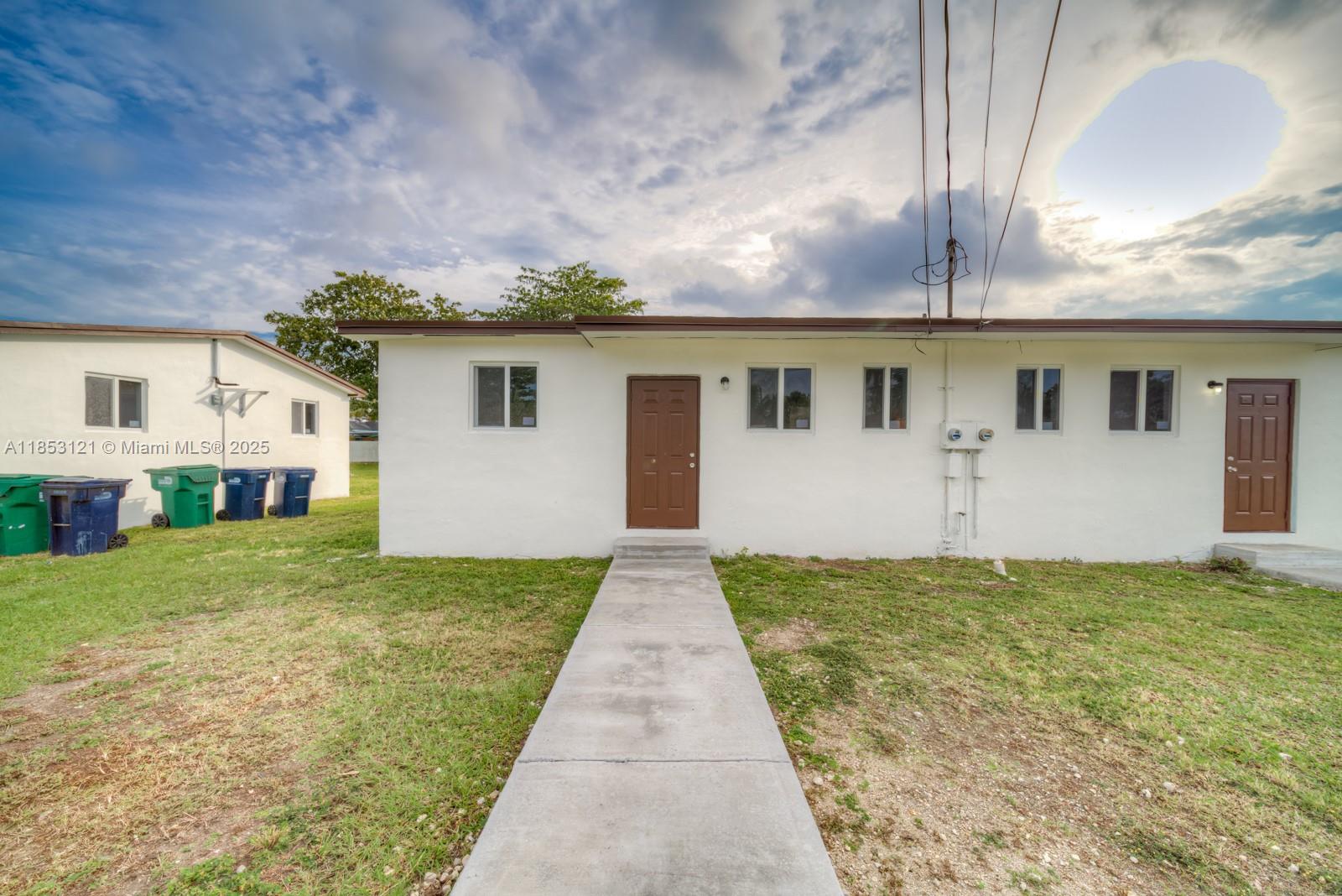 The exterior of a white, single-story building features two brown doors and a concrete walkway — 17715 SW 103rd Ave # 17715, Miami FL 33157, MIAMI, FL