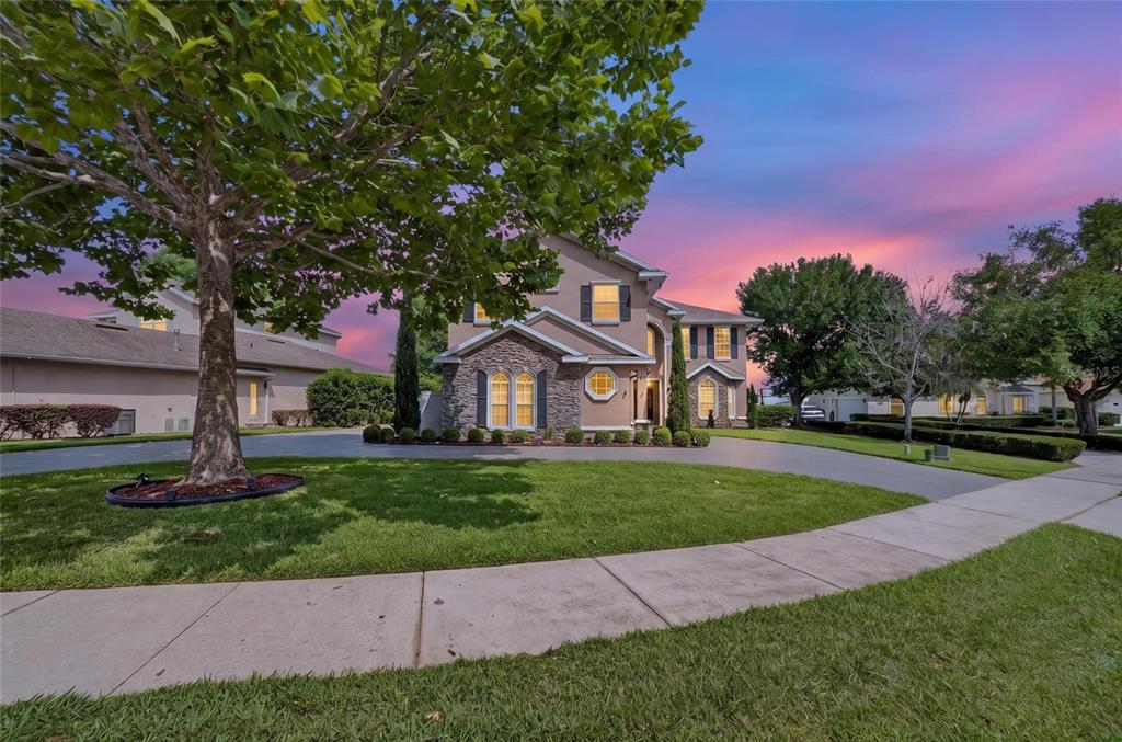 A two-story house with a stone facade, arched windows, and a circular driveway at sunset — 279 ZACHARY WADE STREET, WINTER GARDEN, FL