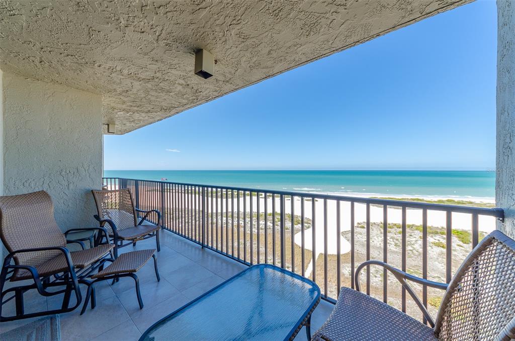 A balcony with outdoor furniture overlooks a sandy beach and the ocean — 1290 GULF BOULEVARD UNIT 907, CLEARWATER, FL