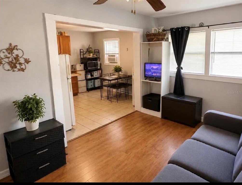 A living room with wood flooring opens into a kitchen with a dining table — 107 LAKE ELIZABETH DRIVE UNIT B, WINTER HAVEN, FL