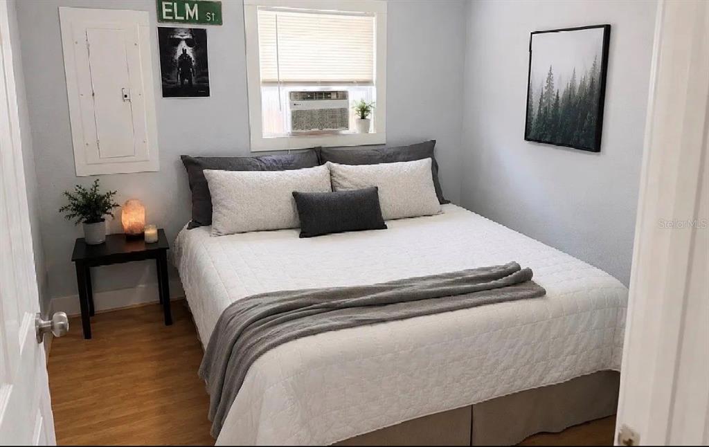 A bedroom features a bed with white bedding, a window air conditioner, and wall decor — 107 LAKE ELIZABETH DRIVE UNIT B, WINTER HAVEN, FL
