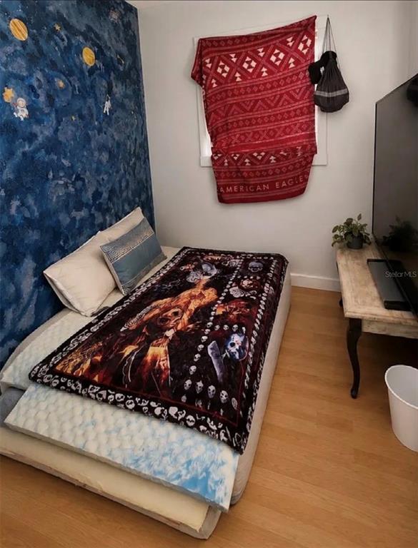A bedroom features a bed with a patterned blanket, a space-themed wall, and a television console — 107 LAKE ELIZABETH DRIVE UNIT B, WINTER HAVEN, FL