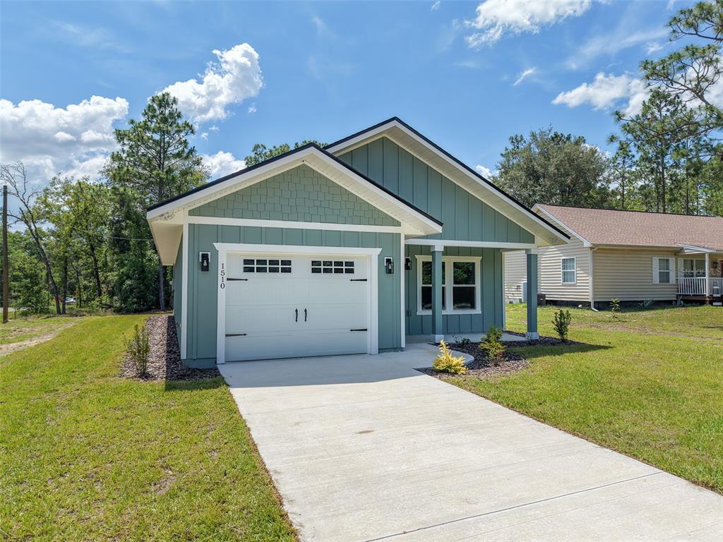 A single-story house with green vertical siding, a white garage door, and a concrete driveway — 1510 NE 156TH TERRACE, WILLISTON, FL