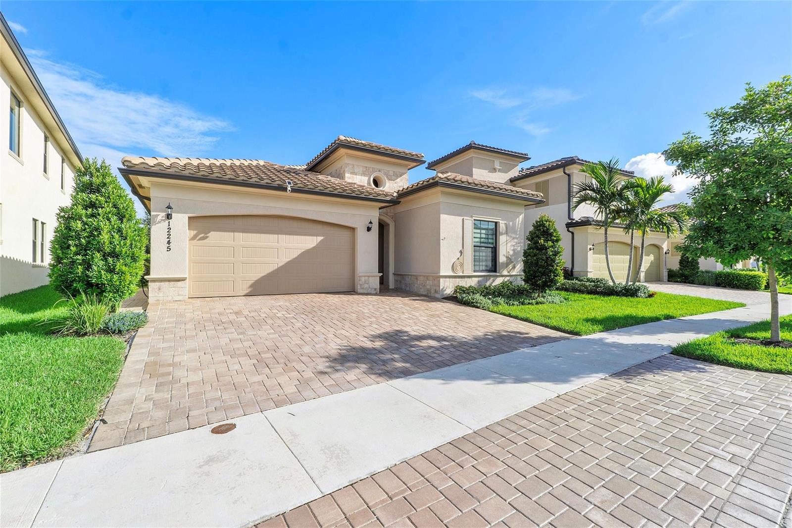 A single-story house with a beige stucco exterior, tile roof, and a paved driveway — 12245 N Baypoint Circle, Parkland FL 33076, PARKLAND, FL