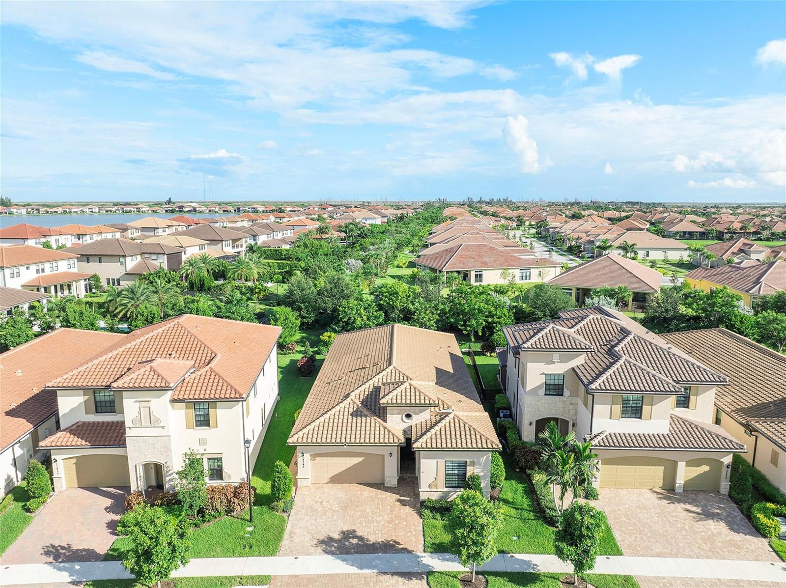 An aerial view shows three suburban houses with tiled roofs and paved driveways — 12245 N Baypoint Circle, Parkland FL 33076, PARKLAND, FL