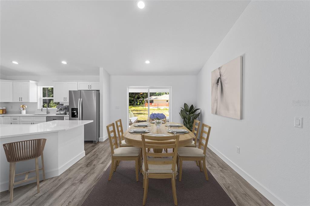 This dining area features a wooden table, six chairs, and a view of the backyard — 6283 NW 61ST STREET, OCALA, FL