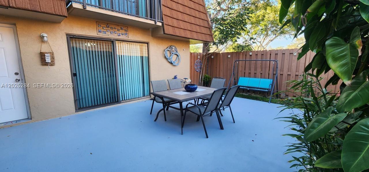 A patio features a dining set, a swing, and a sliding glass door — COOPER CITY, FL