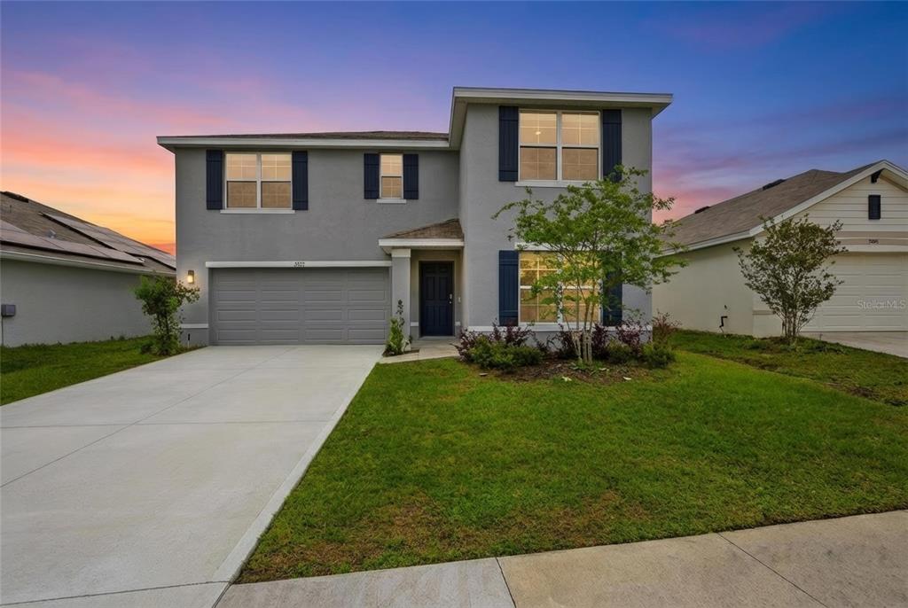 A two-story gray house with a two-car garage and a front lawn at sunset — 5527 SW 43RD COURT, OCALA, FL