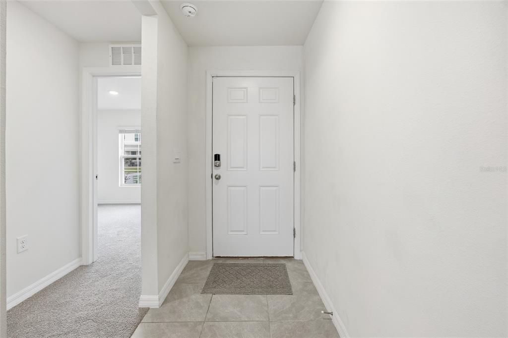 An entryway features a white front door, tiled flooring, and a doorway leading to carpeted space — 5527 SW 43RD COURT, OCALA, FL