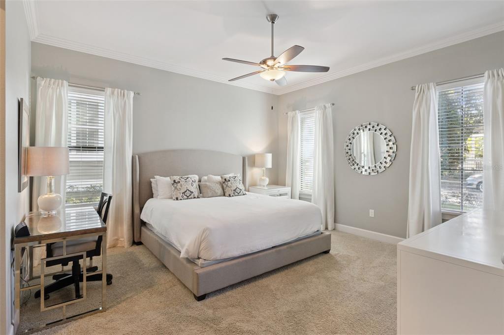 A bedroom features a king-sized bed, a glass desk, and two windows with white curtains — 7423 SPARKLING COURT, REUNION, FL