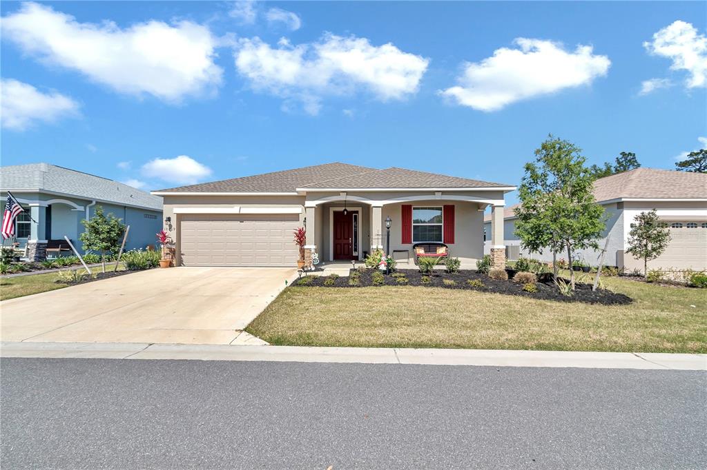 A single-story suburban house features a two-car garage, a covered entryway, and red shutters — 10019 SW 96TH STREET, OCALA, FL