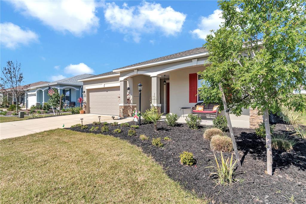 A single-story house with a beige stucco exterior, a two-car garage, and a landscaped yard — 10019 SW 96TH STREET, OCALA, FL