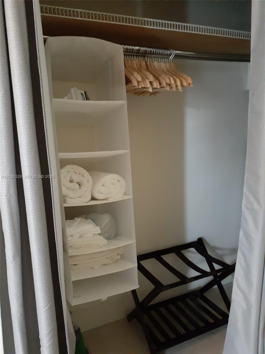 A closet features a hanging fabric organizer, wooden hangers on a rod, and a luggage rack — 2306 Sunshine Blvd, Miramar FL 33023, MIRAMAR, FL