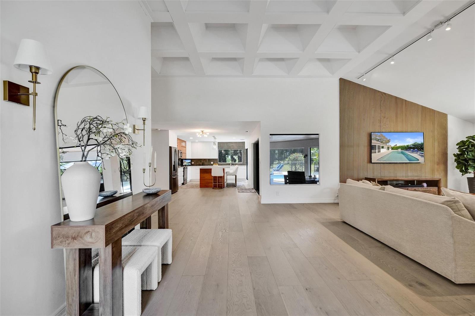 A spacious living room features a coffered ceiling, wood-slat accent wall, and light hardwood floors — 614 Lakewoode Circle W, Delray Beach FL 33445, DELRAY BEACH, FL