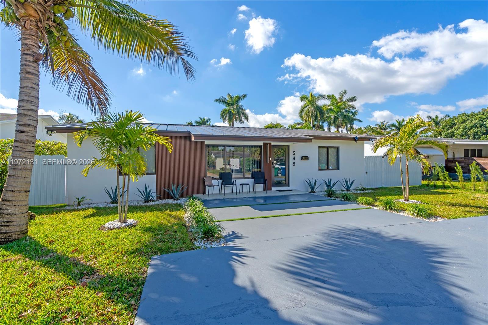 A single-story house features a flat roof, vertical wood siding, and a paved driveway — 348 NE 117th St, Miami FL 33161, MIAMI, FL