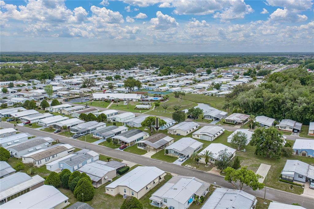 An aerial view shows a manufactured home community with a marked house and surrounding trees — 35116 COLONY HILLS DRIVE, ZEPHYRHILLS, FL