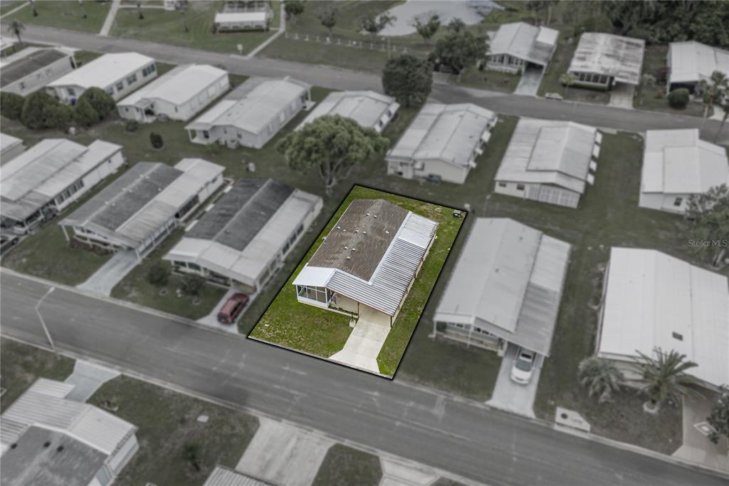 An aerial view shows a single-story manufactured home with a metal roof and carport — 35116 COLONY HILLS DRIVE, ZEPHYRHILLS, FL