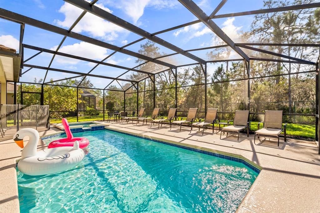 A swimming pool and hot tub are enclosed within a screened-in lanai with lounge chairs — 9128 STROMBOLI COURT, KISSIMMEE, FL