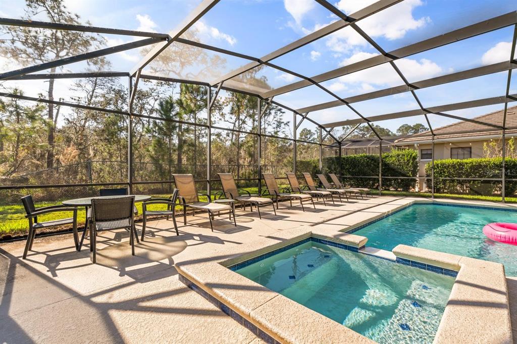 A screened-in patio features a swimming pool, a hot tub, and several lounge chairs — 9128 STROMBOLI COURT, KISSIMMEE, FL