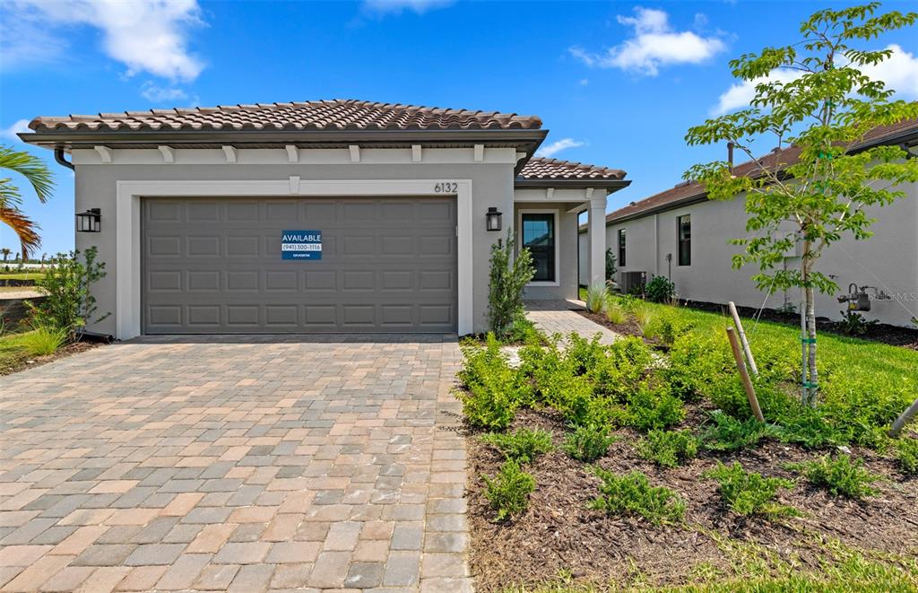A single-story house exterior features a gray garage, tiled roof, and a paved driveway — 5834 TALON PRESERVE DRIVE, NOKOMIS, FL